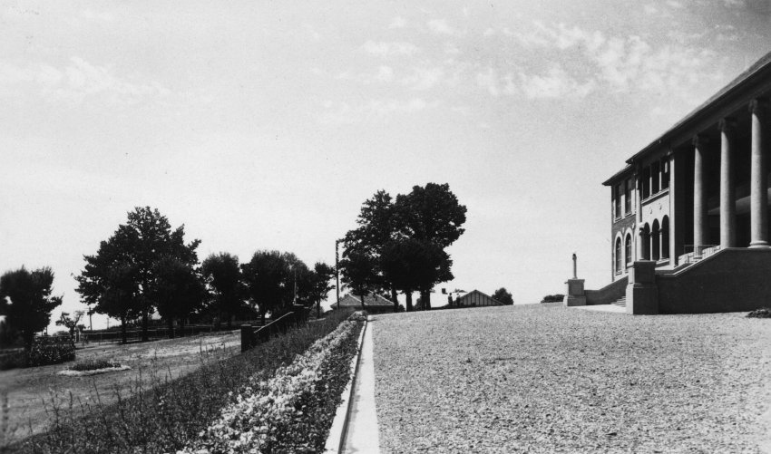 Armidale Teachers' College: View of gravelled area and garden in front of main building (on left), looking east, 1930
