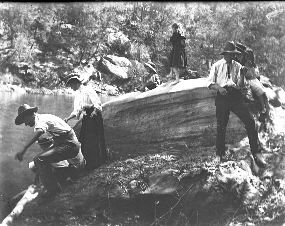Adults and children on rocks by a stream