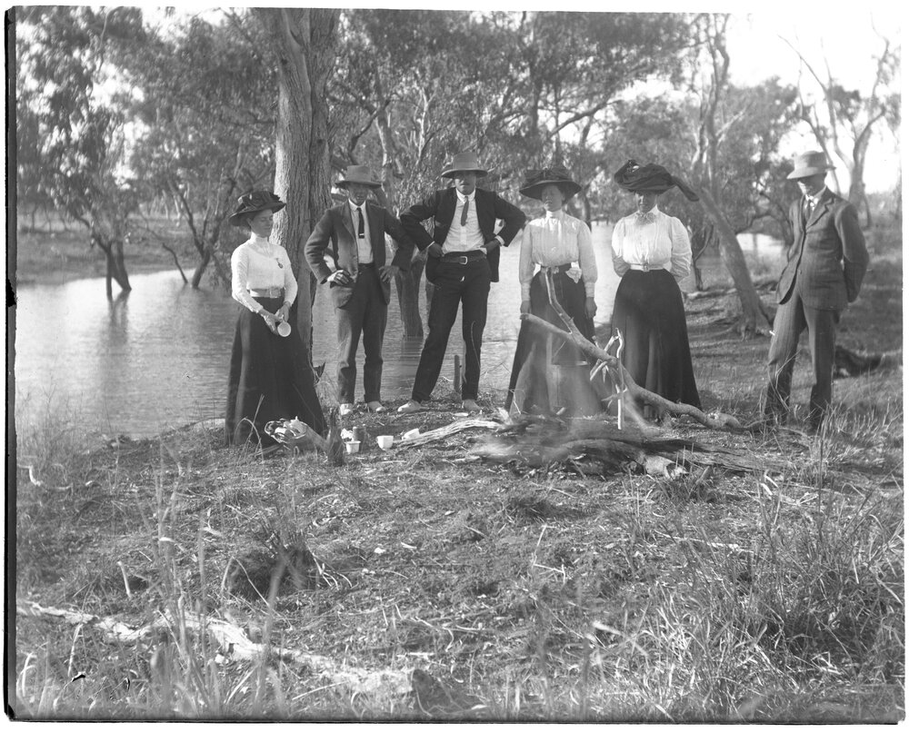 Picnic party beside a river with campfire
