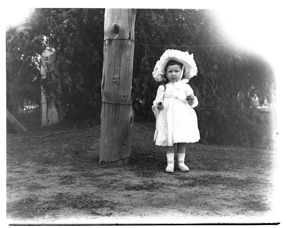 A small girl standing outside holding strawberries