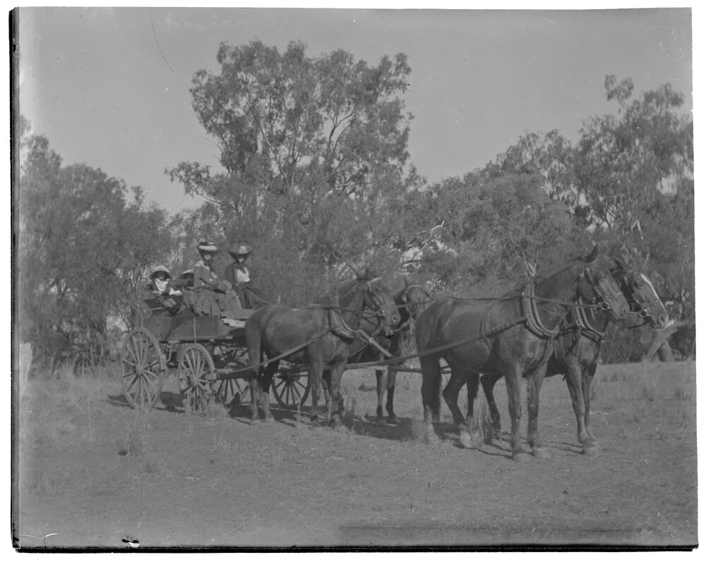 Two women and two children in a carriage pulled by four horses