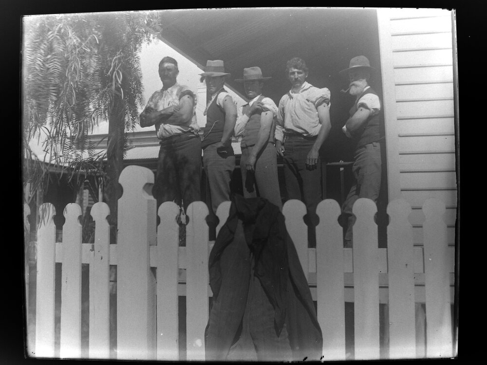 Five men posed on a verandah with left sleeves rolled up