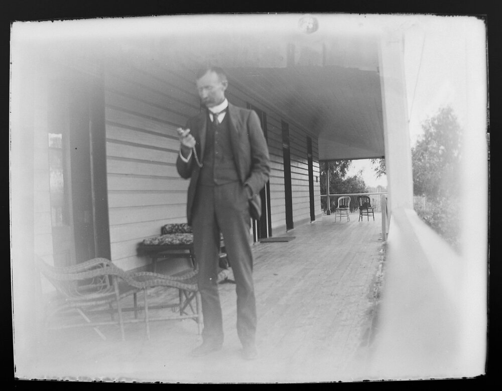[D.M. Cameron] on a verandah looking at his pocket watch