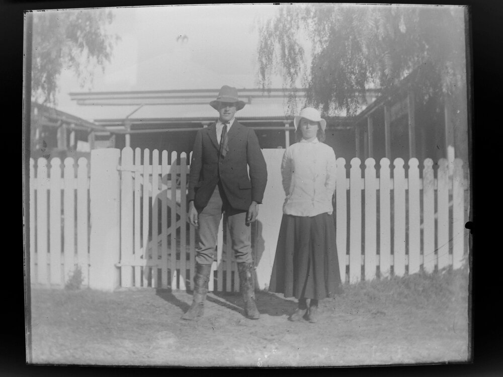 Man and woman standing outside house with picket fence