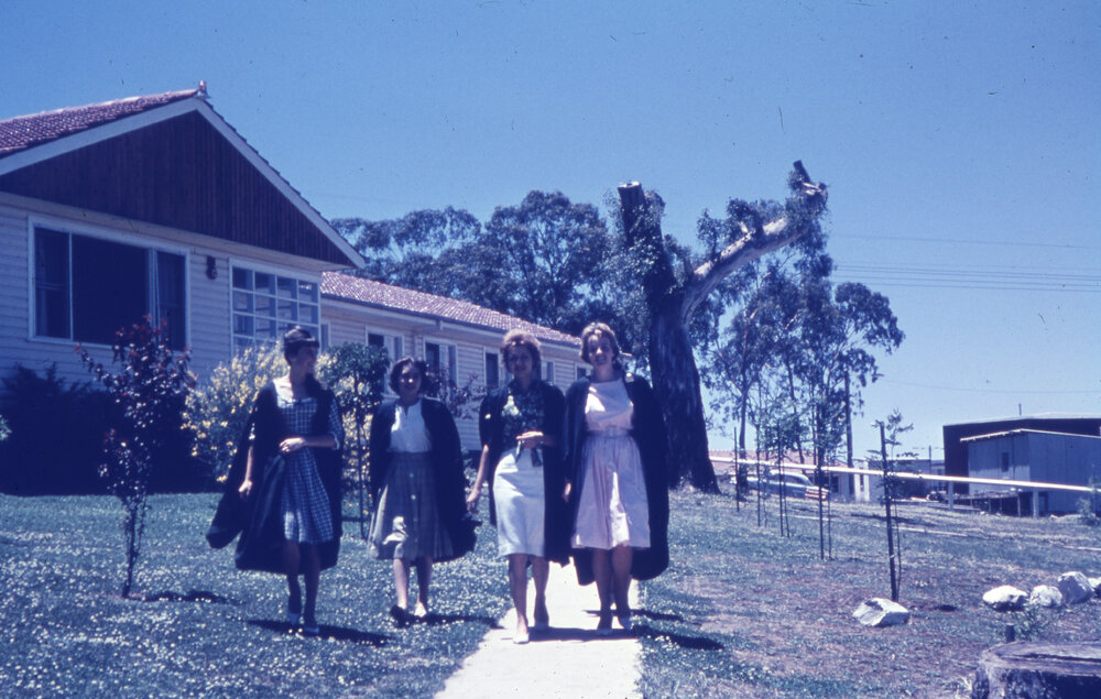 Students in academic robes on campus, UNE
