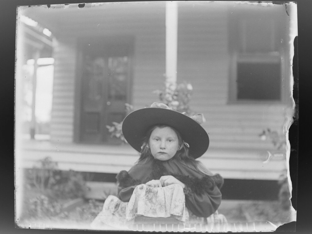 Girl wearing a hat in front of a house