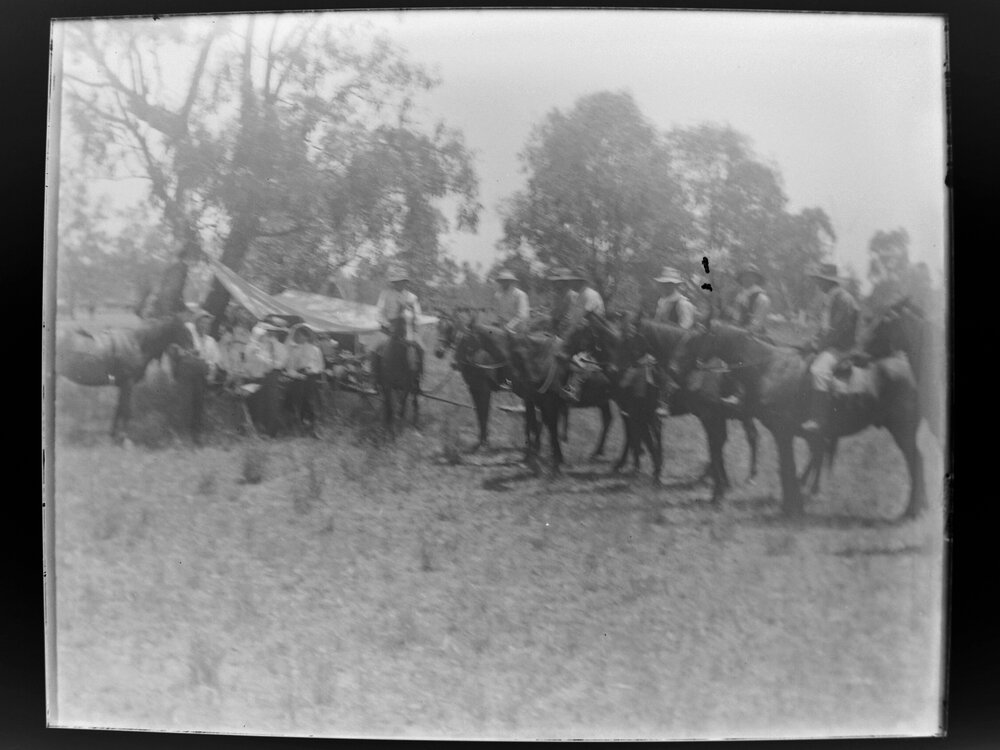 Seven men on horseback near a tent in a clearing