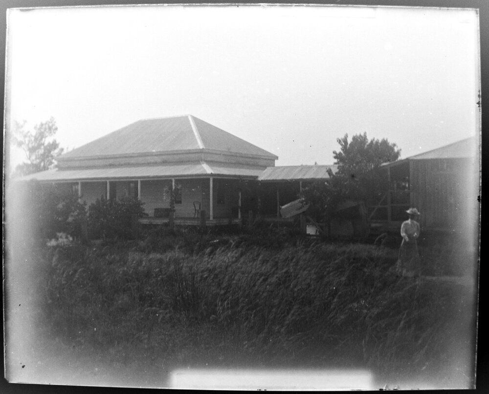 View of a house and sheds with a woman in the foreground