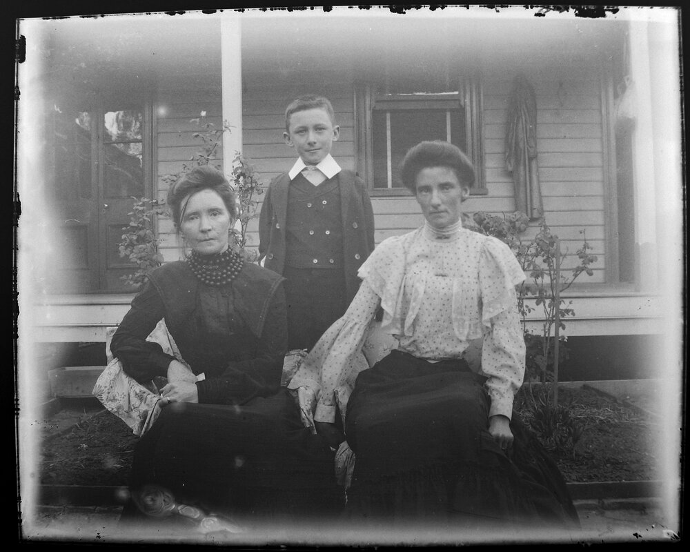 Two women and a boy in front of a house