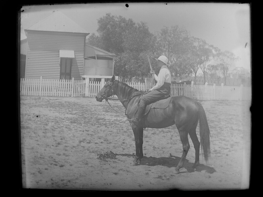 Boy on horse-back, holding a rifle