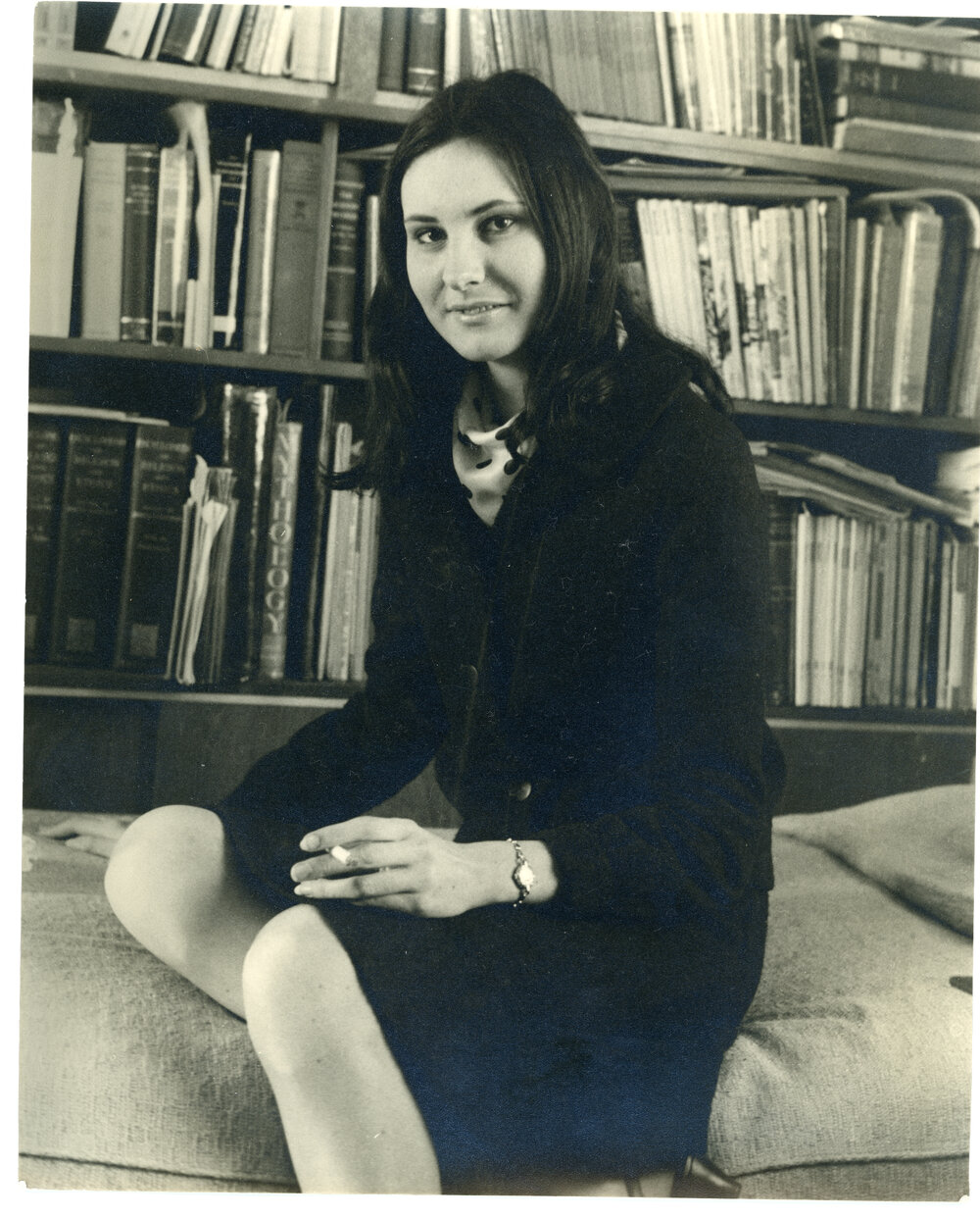Female student seated in front of a bookshelf