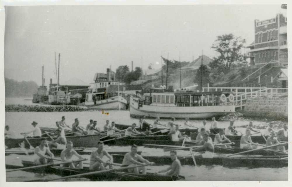 View of row boats and steamers on a river with the town in the background [Lismore]