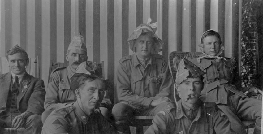 A group of soldiers wearing paper hats