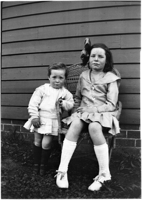 Two unidentified children sitting on a wicker chair probably at 63 Barney Street, Armidale