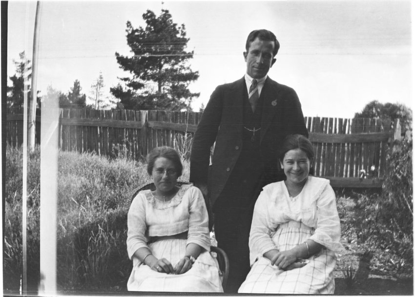 Unidentified man [with RSL pin] standing behind two women