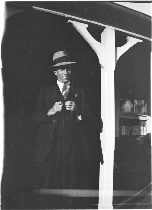 Unidentified man [with RSL pin] standing on the verandah of 63 Barney Street, Armidale