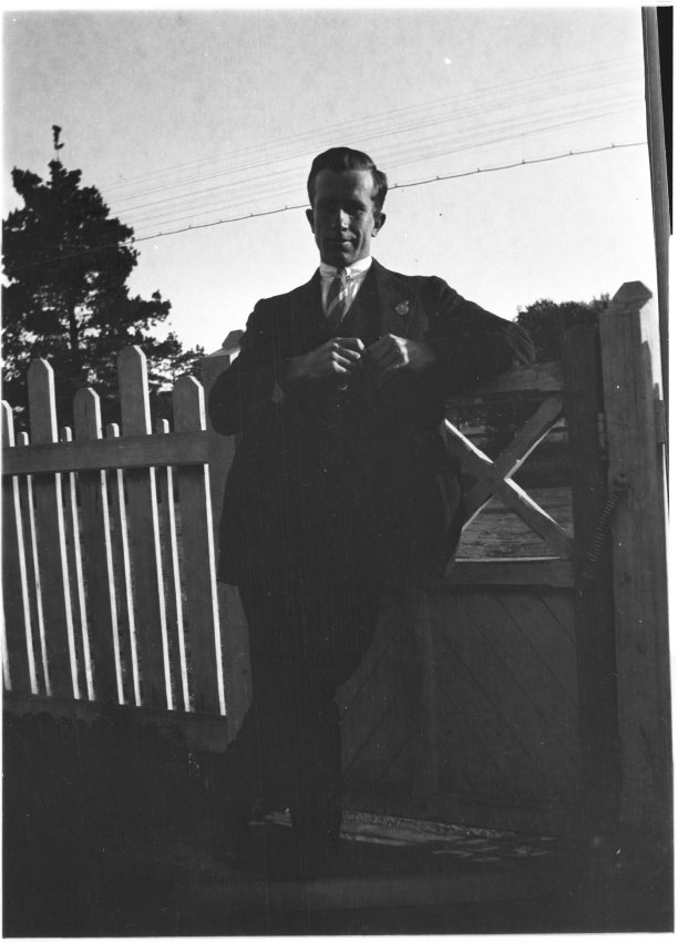 Man [with RSl badge] standing by the front gate of 63 Barney Street, Armidale
