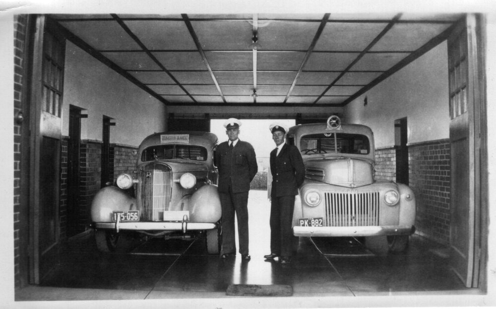 Two ambulance cars parked inside the Armidale District Station, c.1950