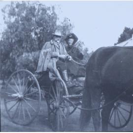 Unidentified couple sitting in a buggy