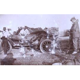 Unidentified men standing around a wrecked car