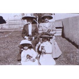 Two unidentified women and two girls all holding puppies