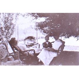Three unidentified women and one boy sitting under trees