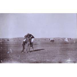 Jockey mounting a racehorse with assistance from a handler