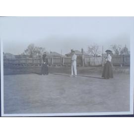 Three unidentified people on a tennis court