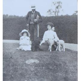 Unidentified man, woman and child with pet lambs