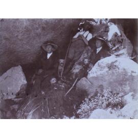 Three people sitting among rocks