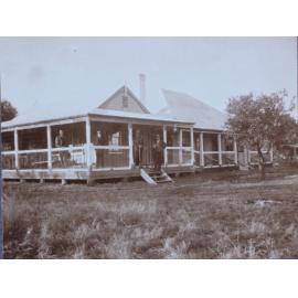 Four gentlemen standing on the verandah of an unidentified residence