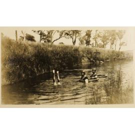 Unidentified woman and two children swimming in the creek