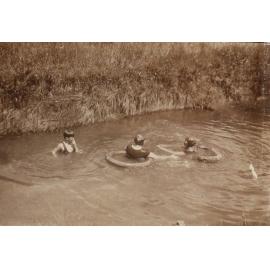 Unidentified woman and two children swimming in the creek