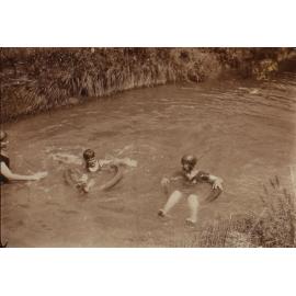 Unidentified woman and two children swimming in the creek