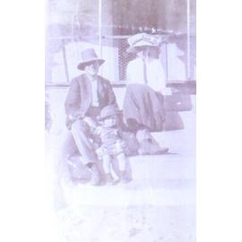 Unidentified man, woman and child sitting on steps