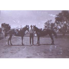 Unidentified man holding two horses