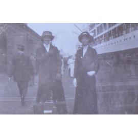 Two unidentified women on the wharf beside a ship