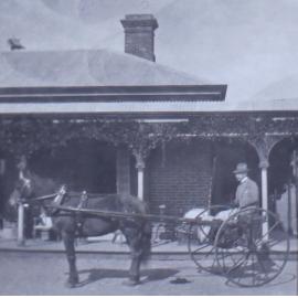Unidentified man with horse and buggy in front of a house