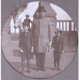 Unidentied man with two boys, another boy in the background on a horse