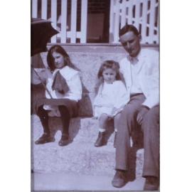 Unidentified man and two girls sitting on steps
