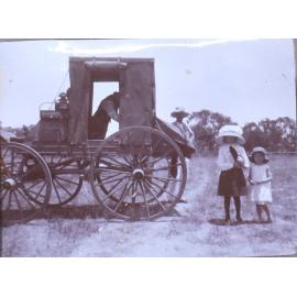 Two unidentified children behind a wagon