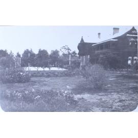 View of gardens, tennis court and house
