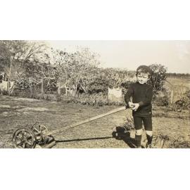 Unidentified boy with push lawn mower