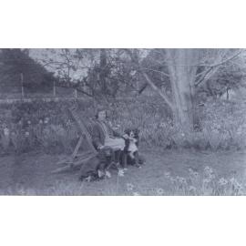 Unidentified girl sitting in the gardens with pet dogs