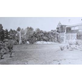 View of gardens, tennis court and house
