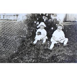 Two unidentified children sitting on the lawn