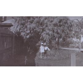 Two unidentified children in the gardens around the tennis court at Saumarez