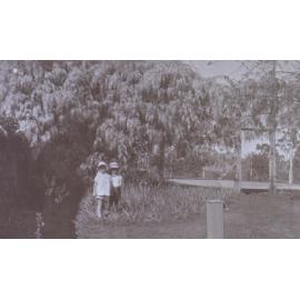 Two unidentified children in the gardens around the tennis court at Saumarez