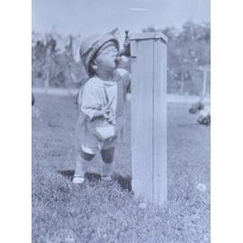Unidentified boy drinking from a tap