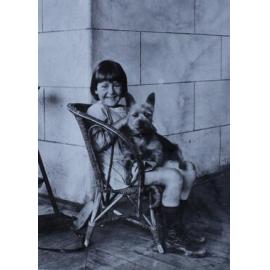Unidentified girl sitting in a chair with a pet dog